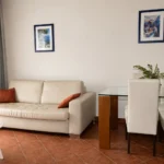 Modern apartment with a pool view, featuring a dining table and a fully equipped kitchen.