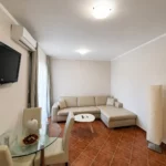 Moderan apartman sa pogledom na bazen sa prostranim dnevnim boravkom, ugaonom garniturom i trpezarijskim stolom.