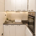 Moderna kuhinja u apartmanu sa pogledom na bazen sa savremenim aparatima i elegantnim dizajnom.