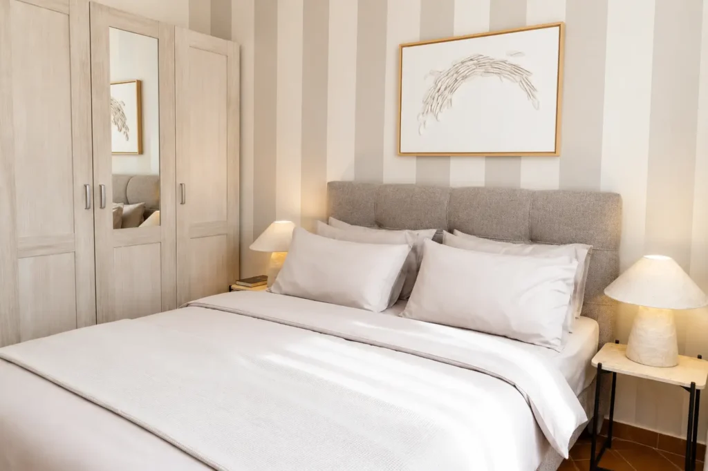 Moderan apartman sa pogledom na bazen sa elegantnom spavaćom sobom, bračnim krevetom i modernim enterijerom.