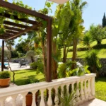 Moderan apartman sa pogledom na bazen okružen mediteranskim vrtom, palmama i uređenom terasom.